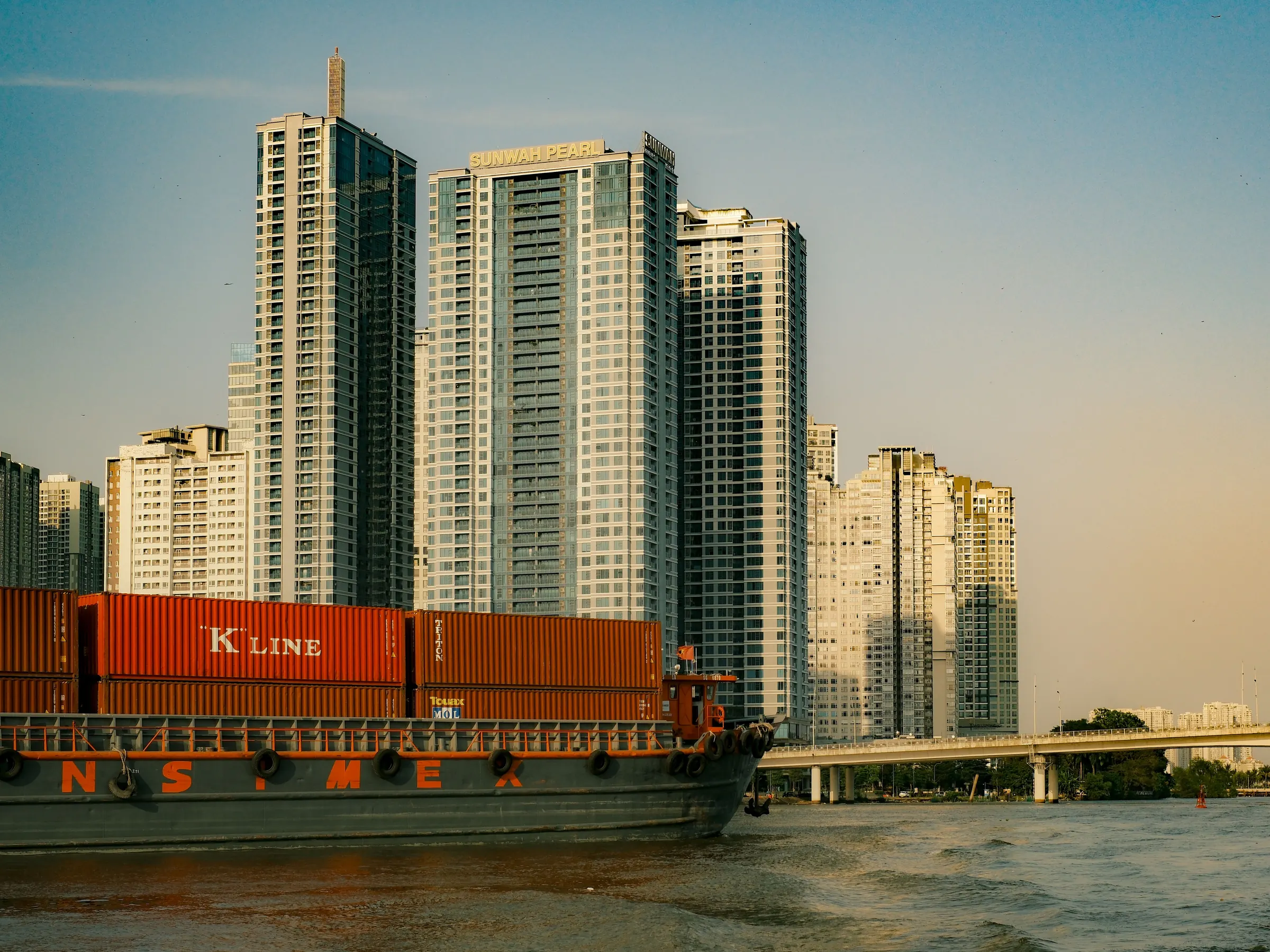 Sà lan container di chuyển trên sông Sài Gòn cạnh các tòa nhà cao tầng